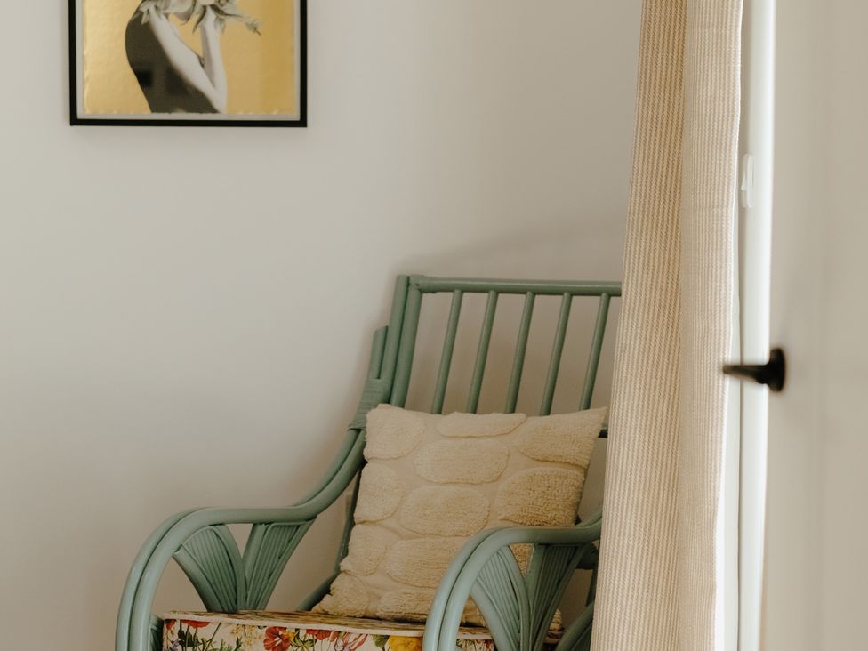 An armchair with a cushion and a framed picture at Baldslow Barn in Battle near Hastings