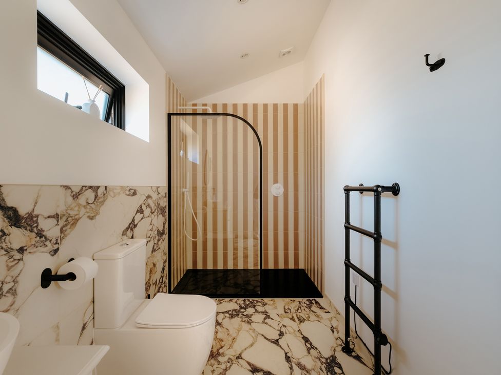 A bathroom with a toilet and glass shower at Baldslow Barn in Battle near Hastings