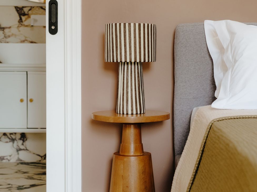 A bedside table with a lamp and a bed at Baldslow Barn in Battle near Hastings