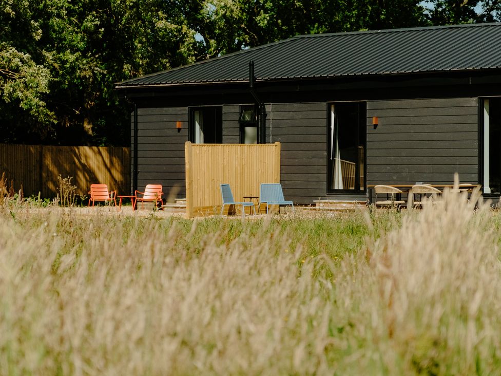A house with chairs in front and a wooden fence at Baldslow Barn in Battle near Hastings