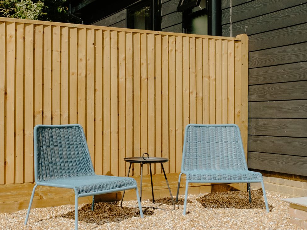 Two blue chairs and a black table in an outdoor area at Baldslow Barn near Hastings