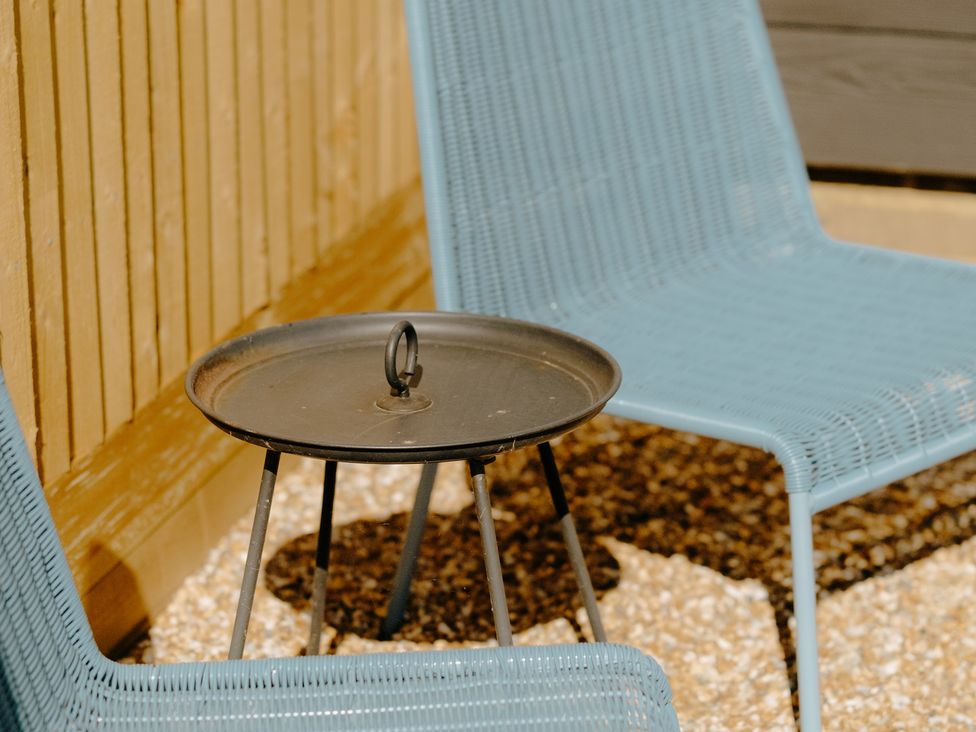Two blue chairs and a round side table in an outdoor seating area at Baldslow Barn in Battle near Hastings