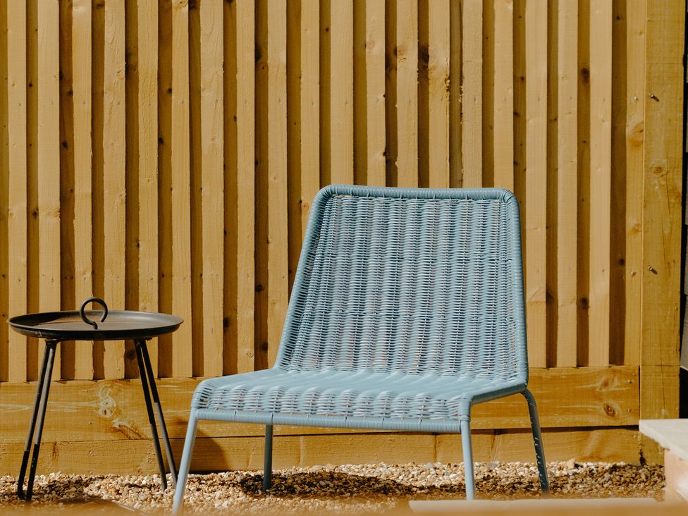 A blue chair and black side table beside a fence at Baldslow Barn near Battle