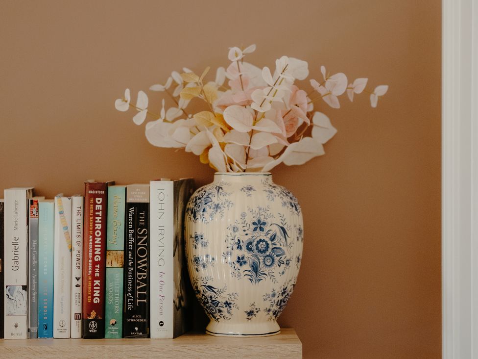 A shelf with books and a vase of flowers at Baldslow Barn near Battle near Hastings