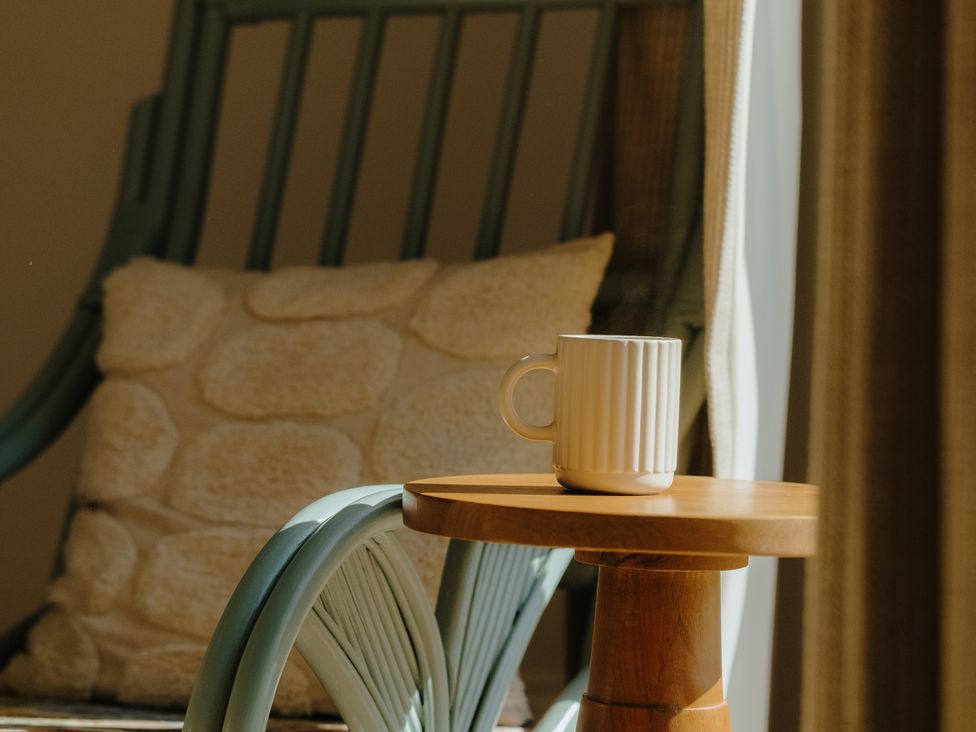 A coffee mug on a side table beside a rocking chair in Baldslow Barn Battle near Hastings