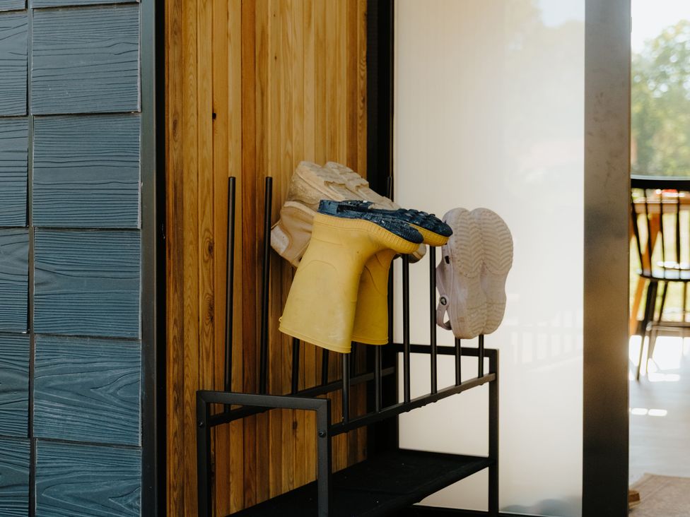 A shoe rack with yellow rubber boots and white shoes at Baldslow Barn in Battle near Hastings