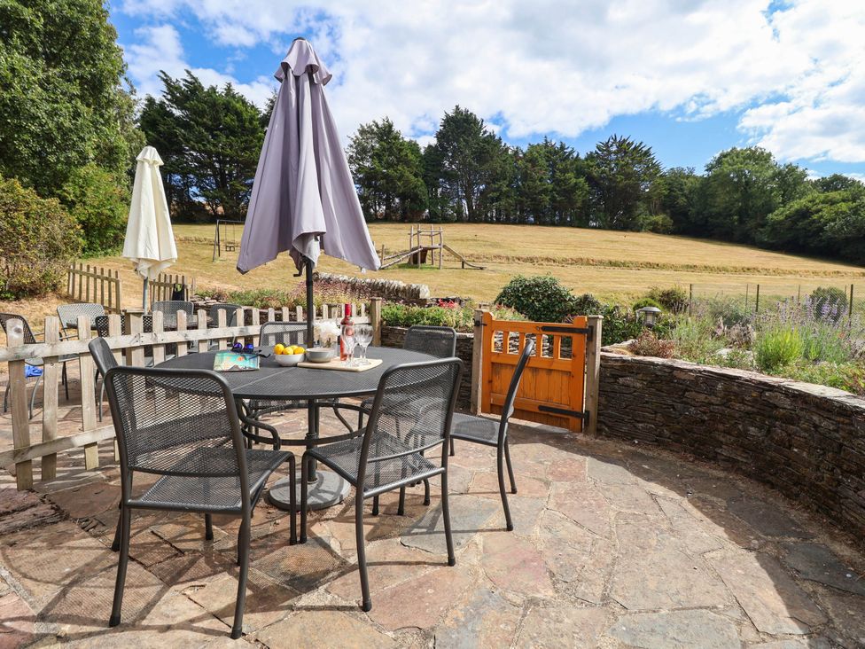 A garden with a table and chairs under an umbrella at Iris at Stancombe Manor Sherford near Chillington