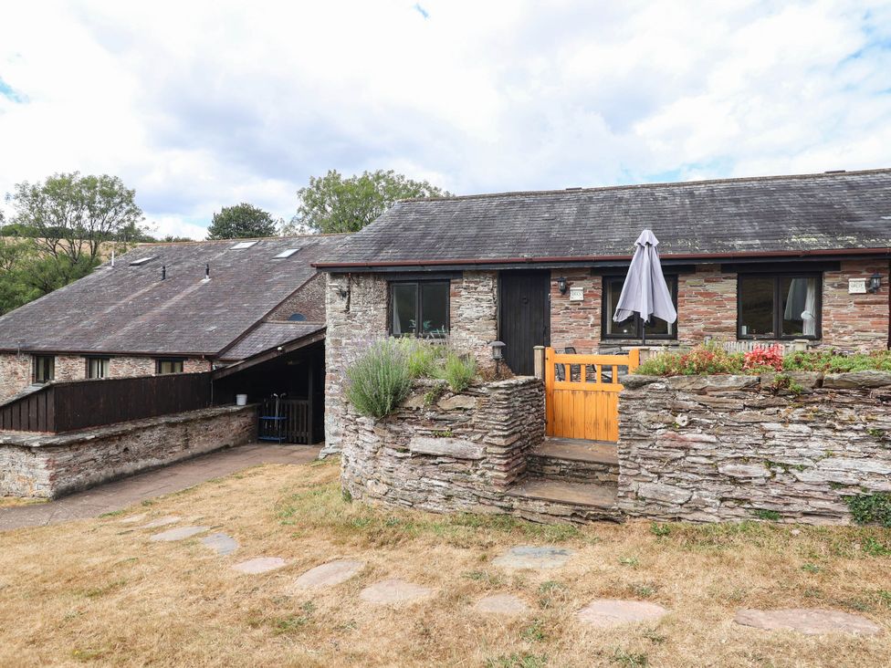 An outdoor view of a building with a stone wall and steps at Iris at Stancombe Manor Sherford near Chillington