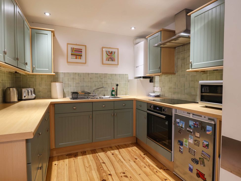 A kitchen with cabinets and appliances at Iris at Stancombe Manor Sherford near Chillington