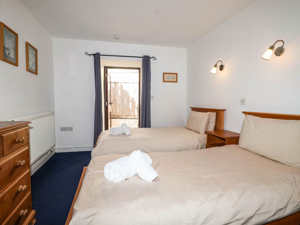 A bedroom with two beds and a door opening to an outdoor area at Iris at Stancombe Manor Sherford near Chillington
