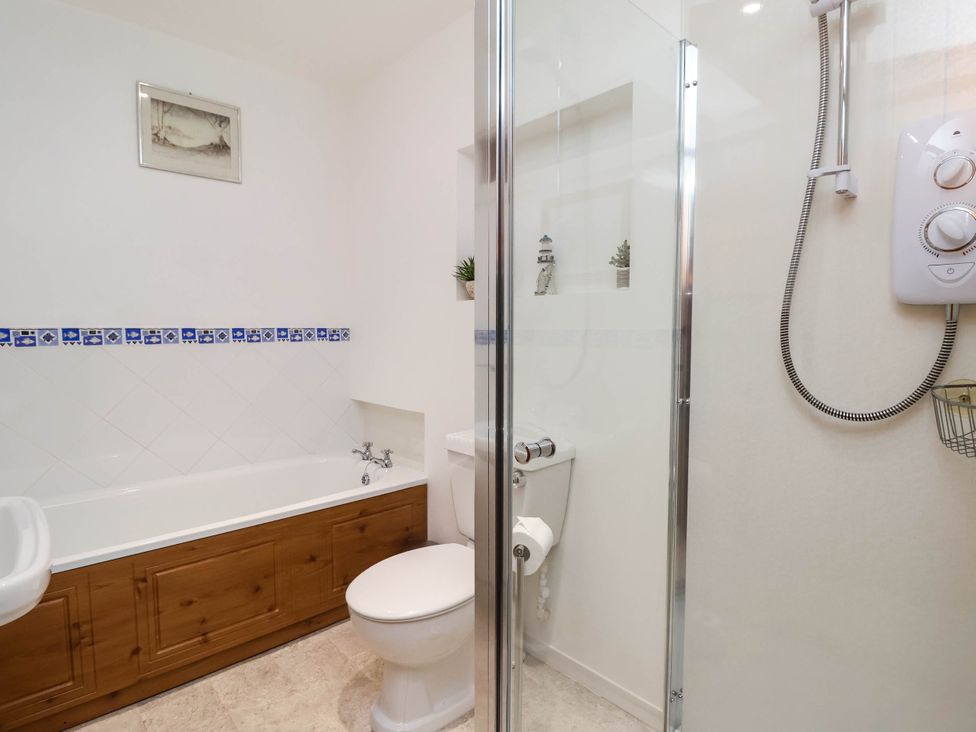 A bathroom with a bathtub, shower, toilet, and sink at Iris at Stancombe Manor Sherford near Chillington