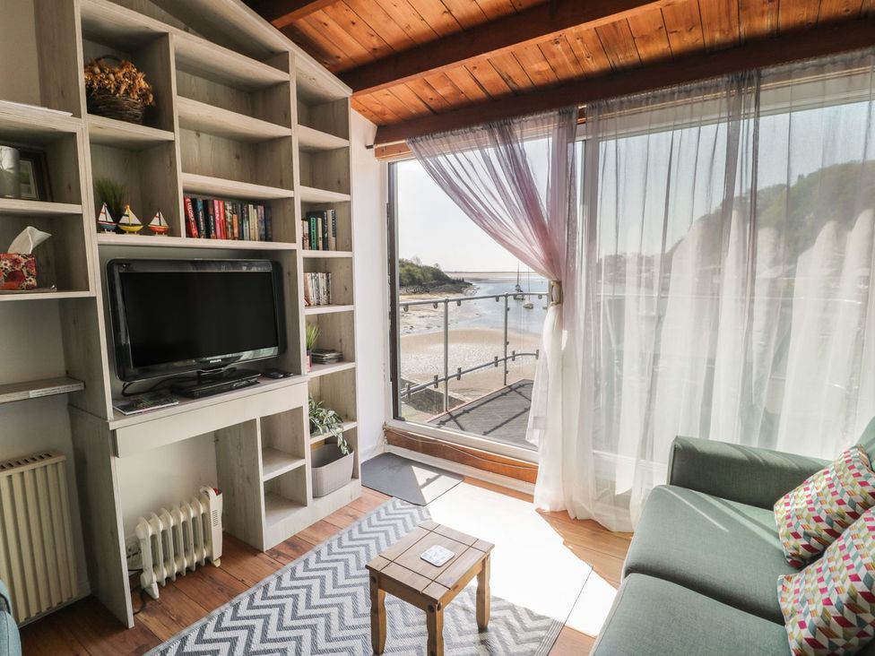 A living room with a television and a bookshelf at Seafarer's Haven in Porthmadog