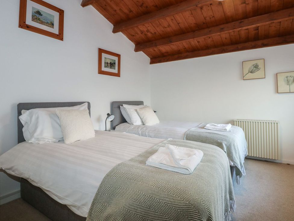 A bedroom with two beds and framed pictures at Seafarer's Haven in Porthmadog