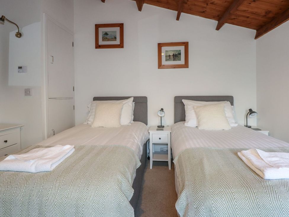 A bedroom with two single beds and bedside tables at Seafarer's Haven in Porthmadog