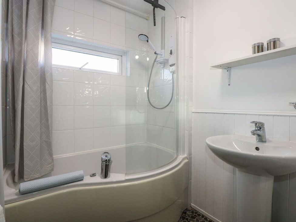 A bathroom with a shower, bathtub, and sink at Seafarer's Haven in Porthmadog