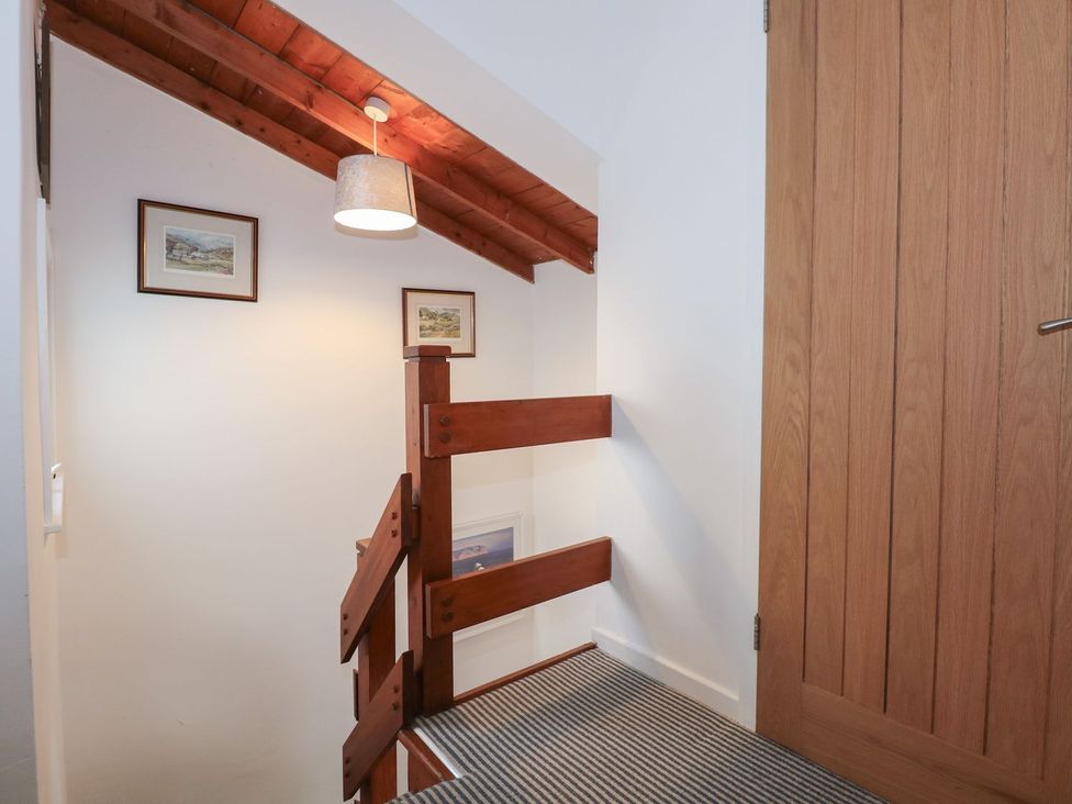 A staircase with a handrail and wall art at Seafarer's Haven in Porthmadog