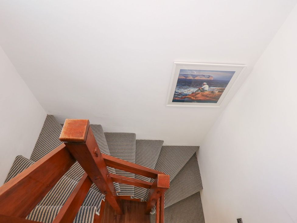A stairwell with wooden railing and a picture frame at Seafarer's Haven in Porthmadog