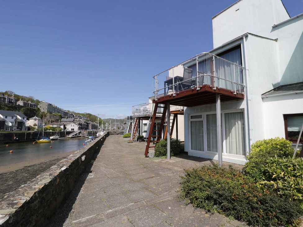 An outdoor view of a waterfront property with a balcony at Seafarer's Haven in Porthmadog