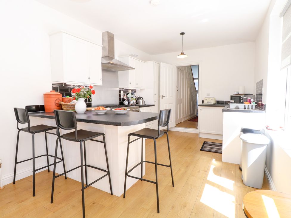 A kitchen with an island and bar stools at 33 North Denes in Great Yarmouth
