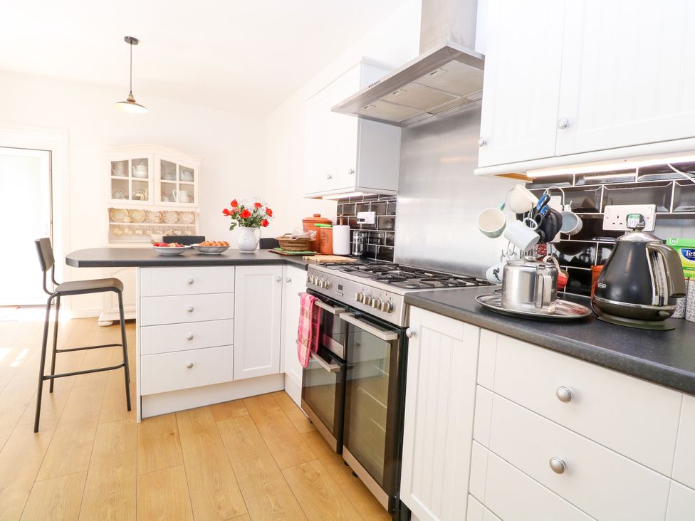 A kitchen with a stove, oven and bar stools at 33 North Denes in Great Yarmouth