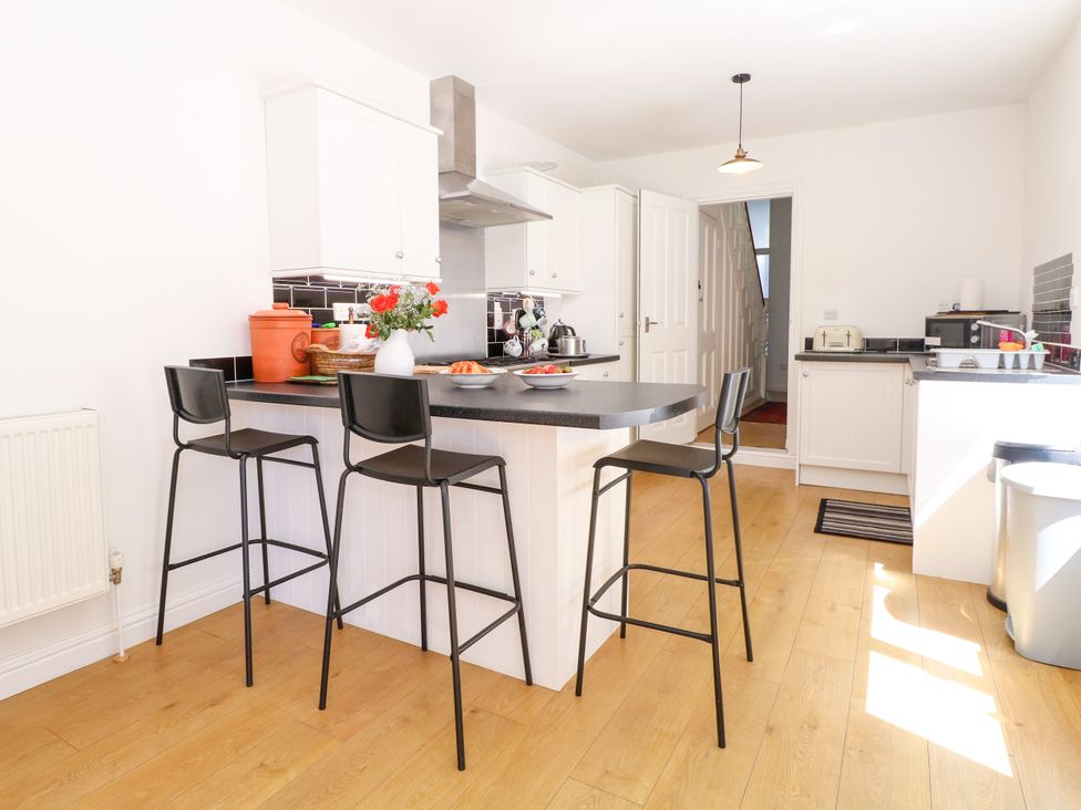 A kitchen with bar stools and a counter at 33 North Denes in Great Yarmouth