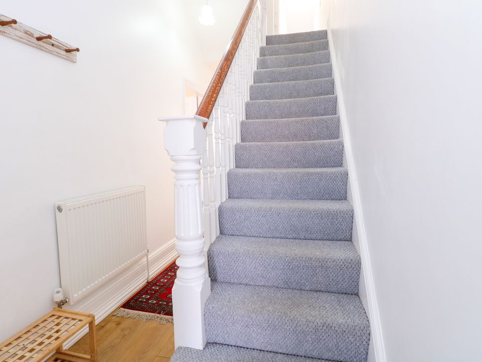 A staircase with grey carpet and a radiator at 33 North Denes in Great Yarmouth