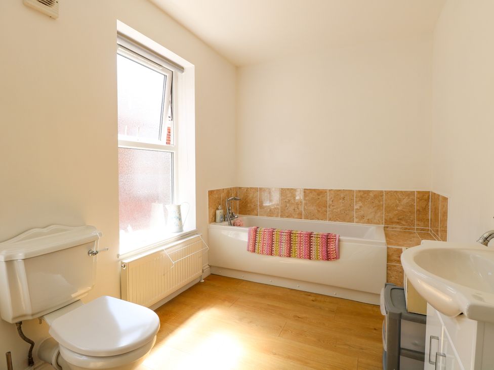 A bathroom with a bathtub, toilet, and sink at 33 North Denes in Great Yarmouth