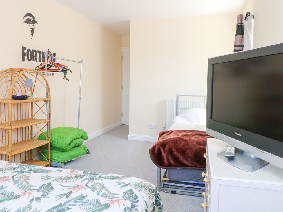 A bedroom with a bed, shelf, and television at 33 North Denes Great Yarmouth