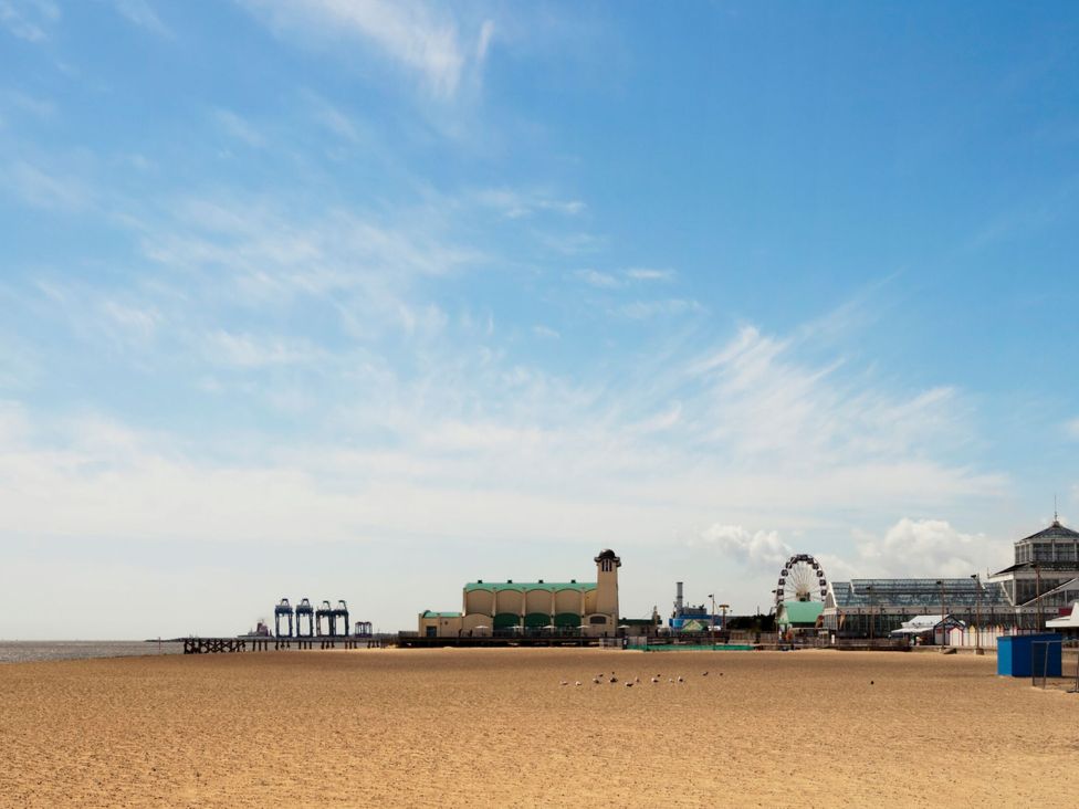 A beach view with a pier and building at 33 North Denes in Great Yarmouth