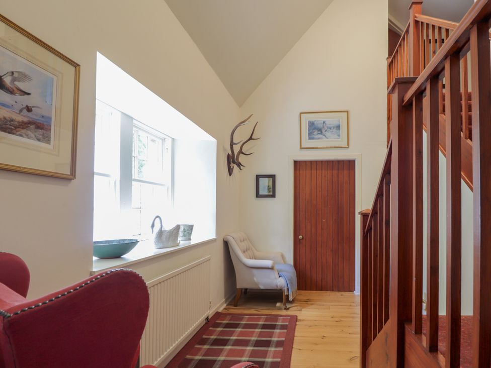 A hallway with a chair and paintings at Tressady Coach House in Rogart