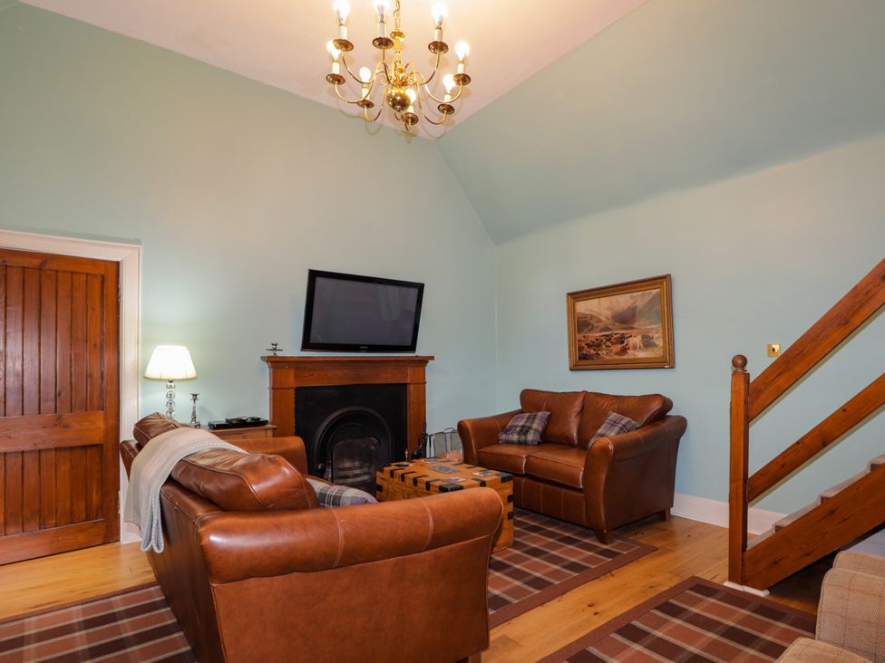 A living room with a fireplace and television at Tressady Coach House in Rogart