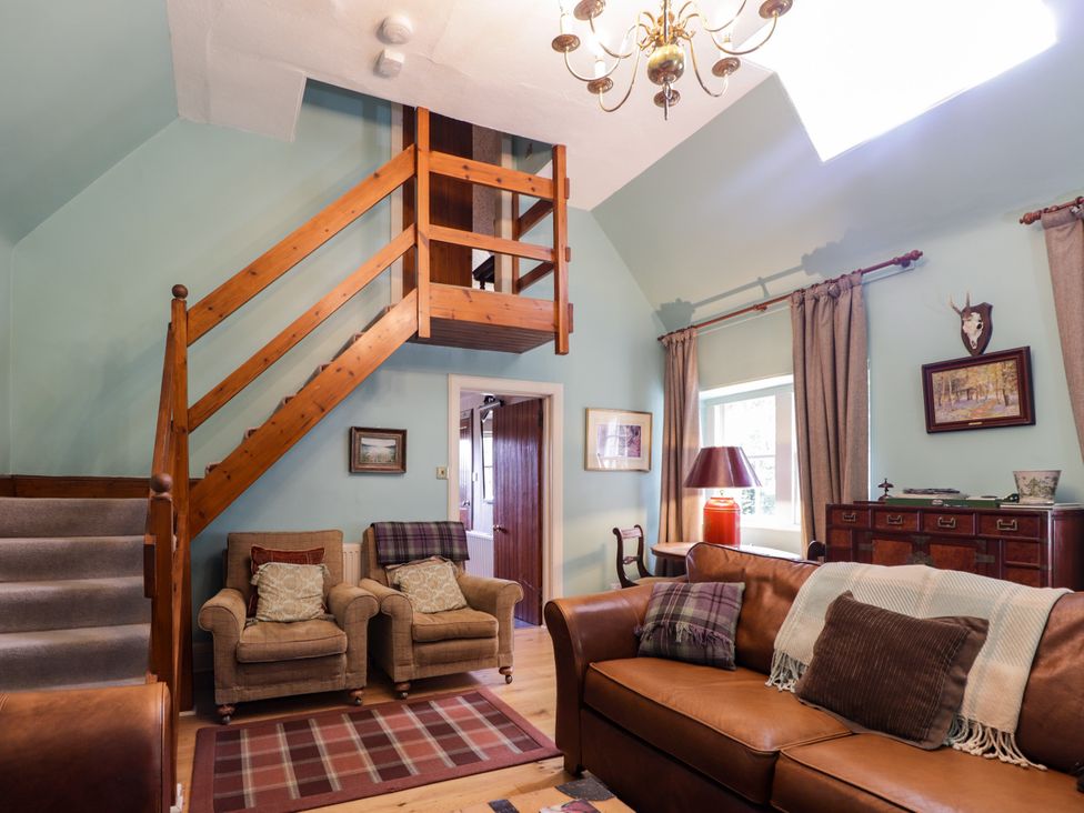 A living room with a staircase and seating area at Tressady Coach House in Rogart