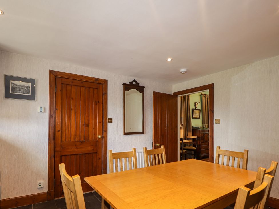 A dining room with a wooden table and chairs at Tressady Coach House in Rogart