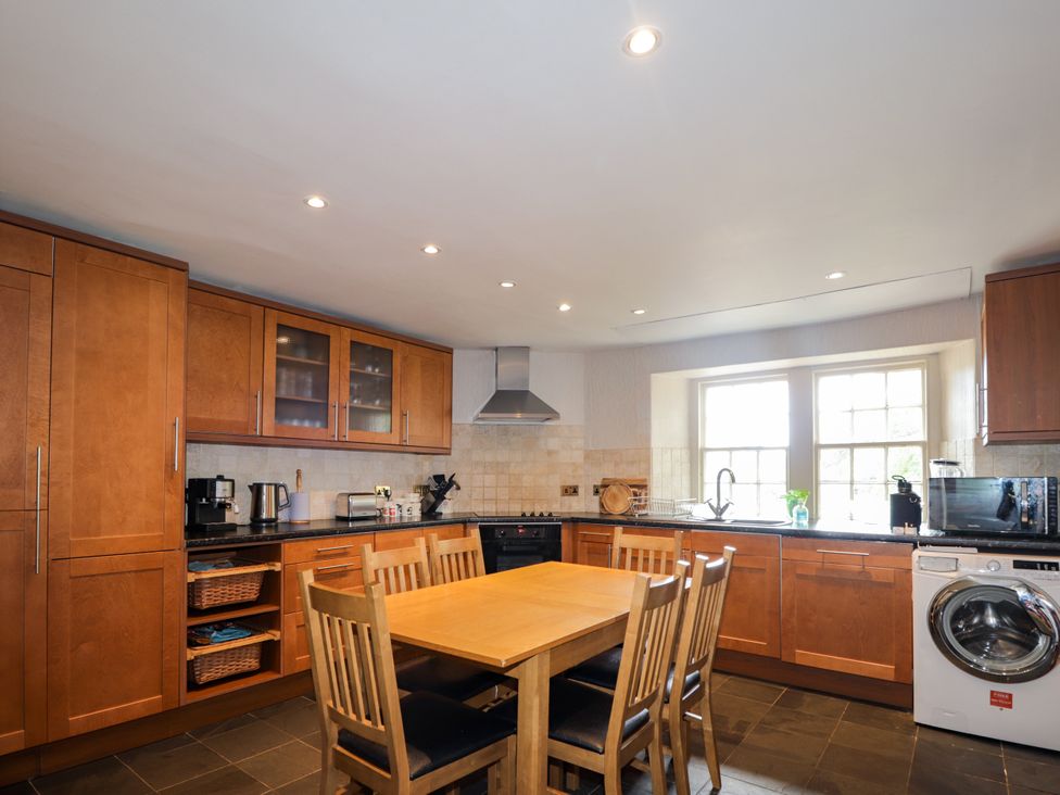 A kitchen with wooden cabinets and a table at Tressady Coach House in Rogart