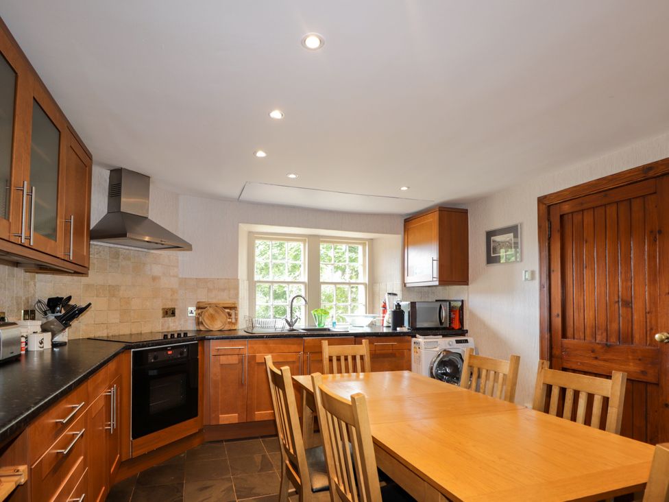 A kitchen with a dining table and appliances at Tressady Coach House in Rogart