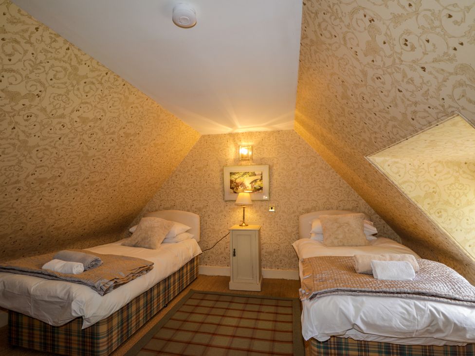 A bedroom with two beds and a bedside table at Tressady Coach House in Rogart
