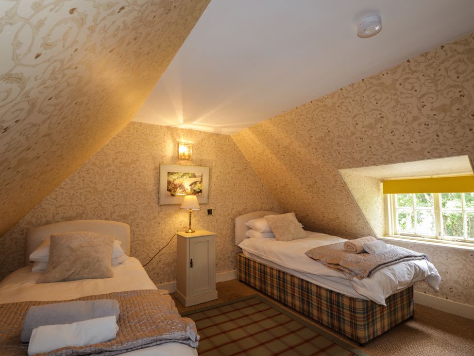 A bedroom with two beds and a lamp at Tressady Coach House in Rogart