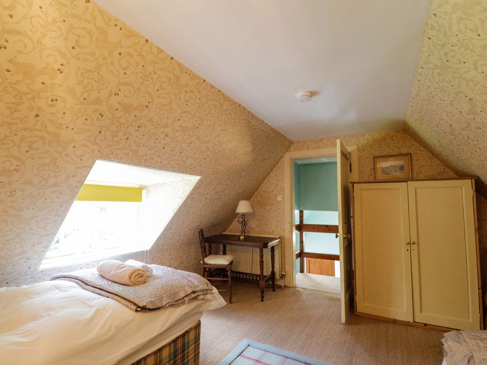 A bedroom with a bed and desk at Tressady Coach House in Rogart