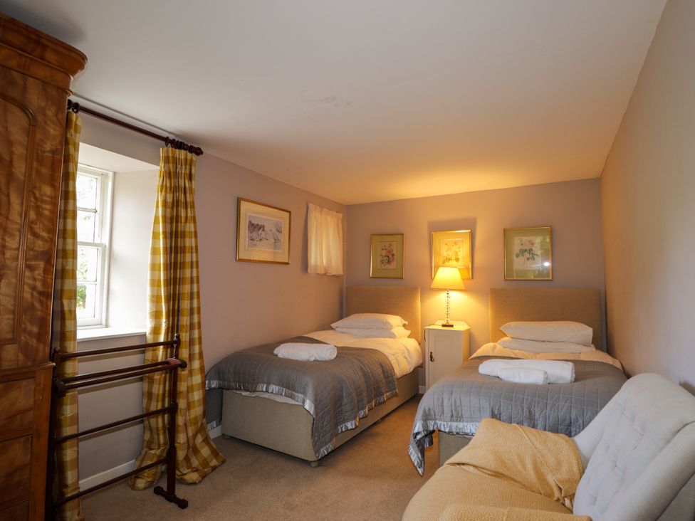 A bedroom with two beds and a bedside table at Tressady Coach House in Rogart