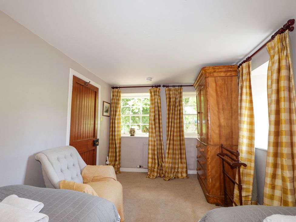A bedroom with a door, window and curtains at Tressady Coach House in Rogart