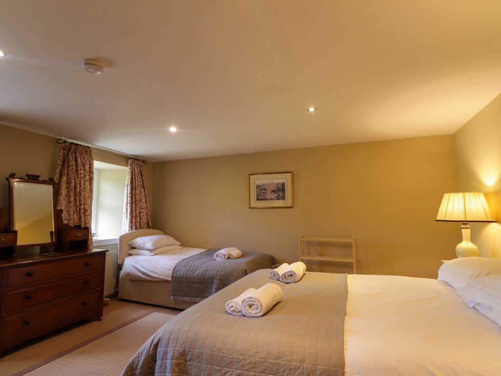 A bedroom with two beds and a mirror at Tressady Coach House in Rogart