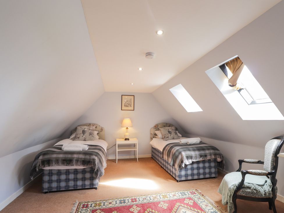 A bedroom with two beds and a nightstand at Tressady Coach House in Rogart