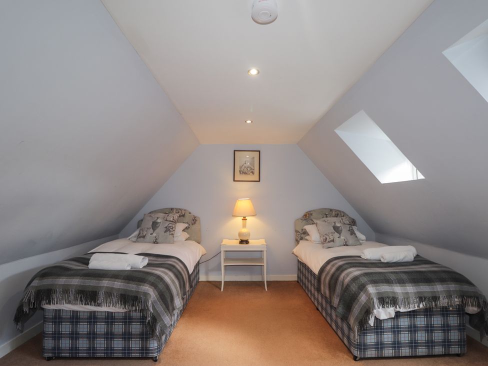 A bedroom with two beds and a lamp at Tressady Coach House in Rogart