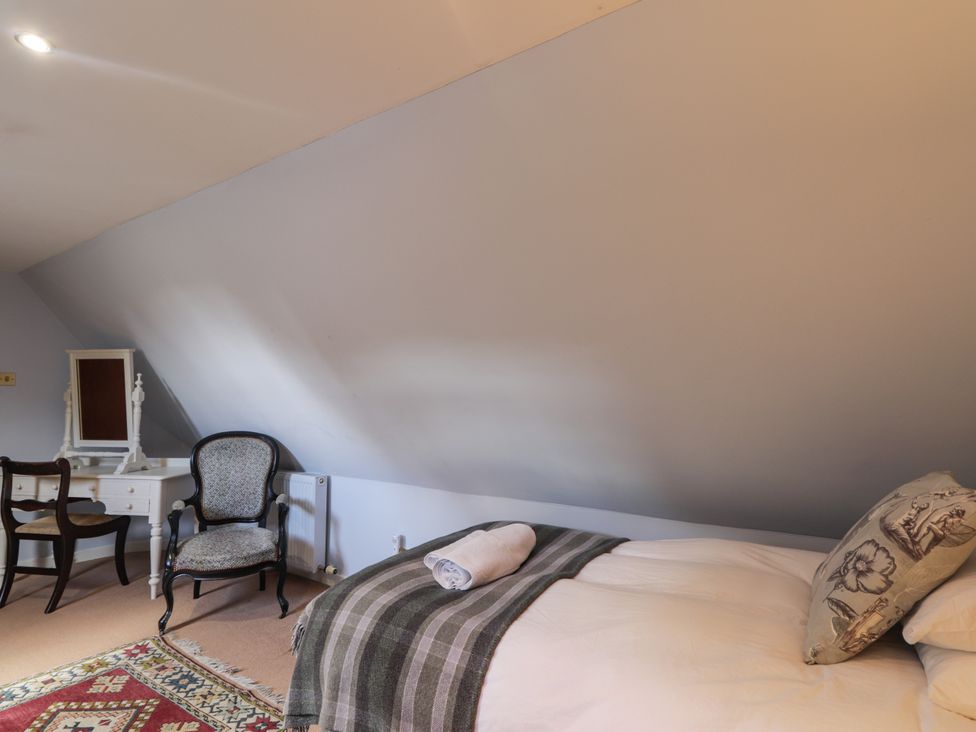 A bedroom with a bed and chair at Tressady Coach House in Rogart