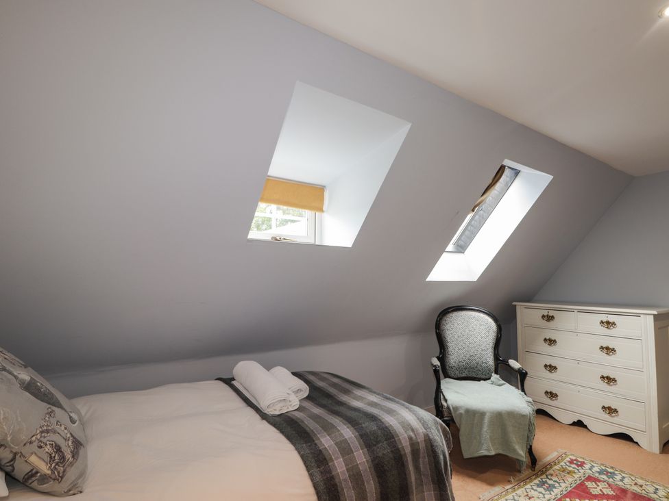 A bedroom with a single bed and an armchair at Tressady Coach House in Rogart