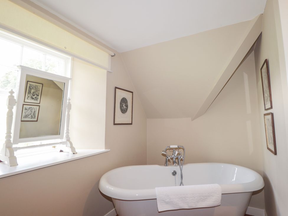 A bathroom with a bathtub and a window at Tressady Coach House in Rogart