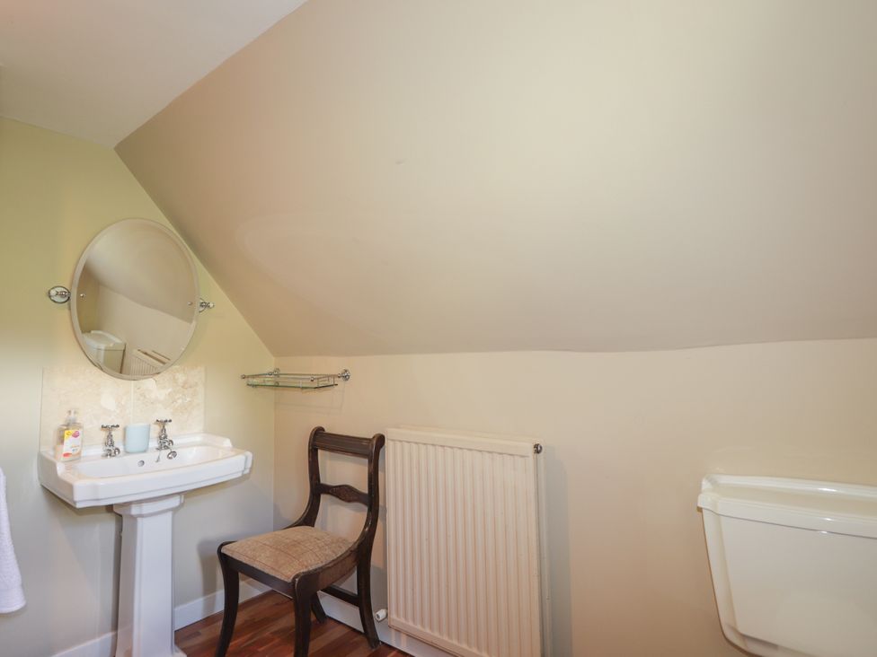 A bathroom with a sink, toilet, and mirror at Tressady Coach House in Rogart