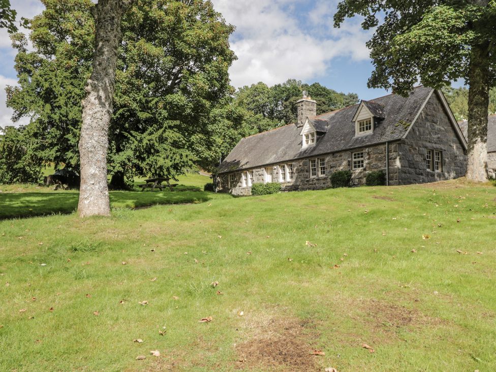 A cottage surrounded by trees and grass at Tressady Coach House in Rogart