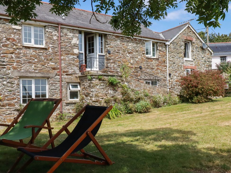 An outdoor area with a stone building and deck chairs at The Granary