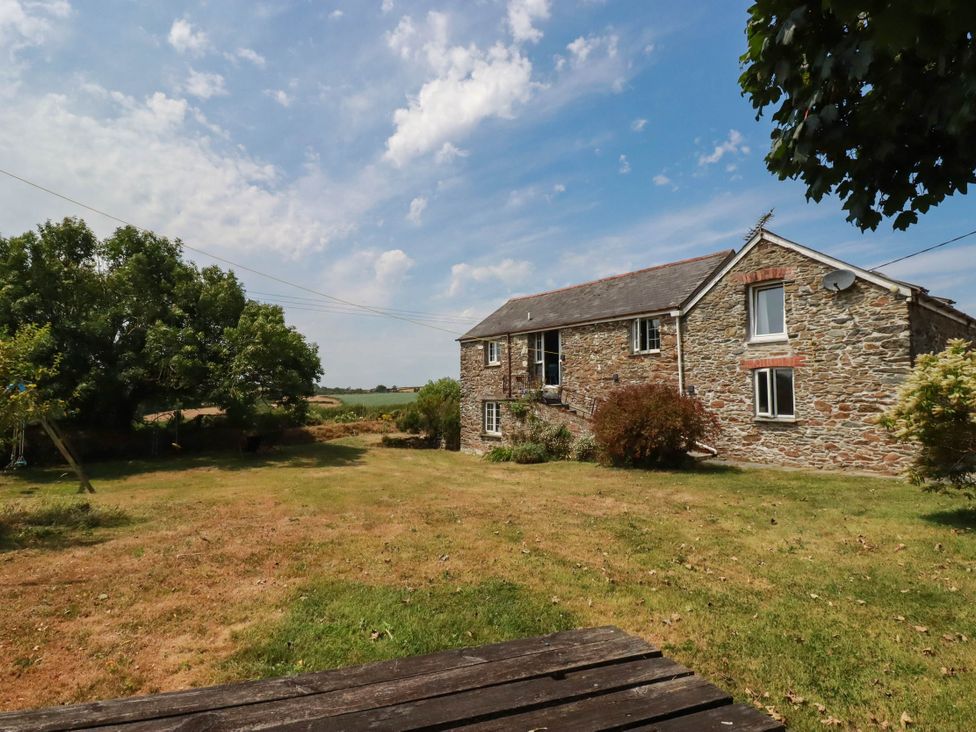 A house with windows and a door surrounded by grass and trees at The Granary